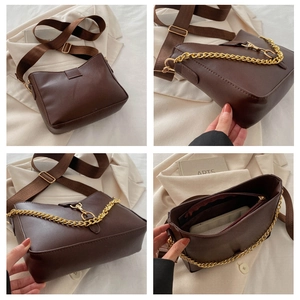 Detalle del bolso de hombro marrón con cadena dorada y compartimentos interiores