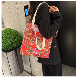 Detail view of large red canvas tote bag with traditional floral and dragon patterns