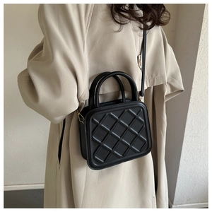 Close-up of black quilted crossbody bag with golden hardware and slender shoulder strap