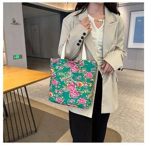 Detail of green floral canvas tote bag with traditional Chinese peony pattern on shoulder
