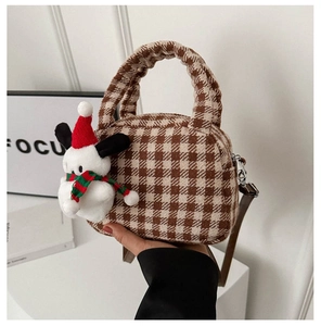 Dettaglio della borsa a quadri marroni con ciondolo in peluche e manico increspato