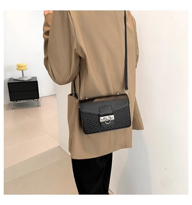 Close-up of black woven leather shoulder bag featuring a stylish metal ring buckle closure