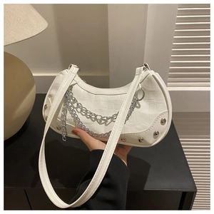 Détail du sac blanc texture crocodile avec chaînes argentées et rivets sur table noire