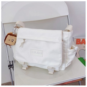 Vue détaillée du sac messager en nylon blanc avec bandoulière et pendentif peluche toast