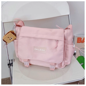 Détail du sac bandoulière rose en nylon avec boucle de fermeture et breloque biscuit