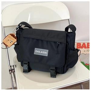 Détail du sac de messager en nylon noir avec boucles et breloque peluche de pain grillé