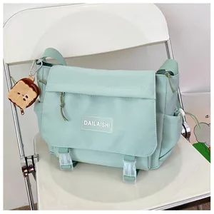 Détail du sac messager en nylon vert menthe avec boucles et breloque toast peluche
