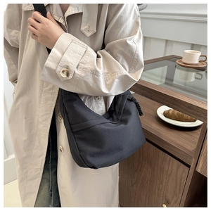 Detail of a black crescent dumpling bag with drawstring and fabric strap in a cafe