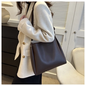 Detail of a dark brown leather tote bag paired with a cream-colored wool coat in a chic room
