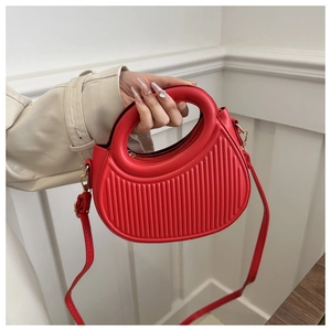 Detail der roten Halbmond-Handtasche mit vertikaler Streifenprägung und Goldbeschlägen