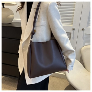 Detail of a dark brown leather tote bag showing smooth texture and stylish knot on the strap
