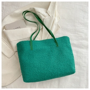 Gros plan d'un sac cabas en fausse fourrure verte avec anses élégantes en cuir
