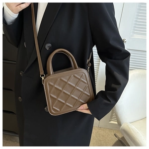 Detail of a brown quilted leather crossbody bag with adjustable strap on a model