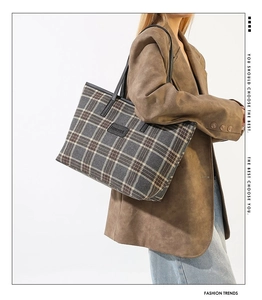 Close-up of vintage plaid tote bag featuring leather brand tag and woven texture detail