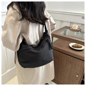 Detail of black nylon crescent hobo bag with braided knot strap on shoulder
