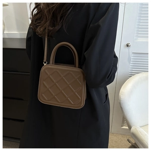 Close-up of brown quilted leather bag with elegant stitching and metallic buckle details