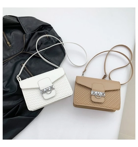 Detail of white and camel flap bags with heart embossed patterns and silver metal buckles