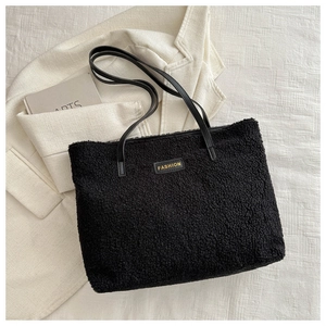 Détail d'un sac cabas noir en peluche douce avec de longues anses en similicuir élégantes