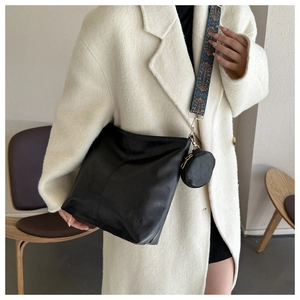 Detail of black tote bag with retro patterned wide strap and small round coin purse charm