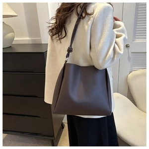 Detail view of deep brown faux leather bucket bag with stylish knotted shoulder strap