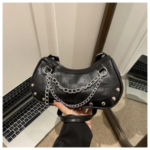 Détail du sac noir à motif crocodile avec chaîne argentée et clous métalliques décoratifs
