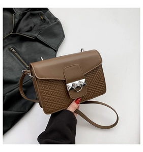 Detail of a brown leather crossbody bag with heart-shaped embossing and silver metal lock