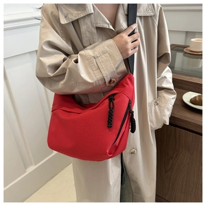Detail of a bright red crescent crossbody bag worn with a beige trench coat