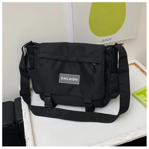 Détail du sac messager en nylon noir avec bandoulière réglable et logo de la marque