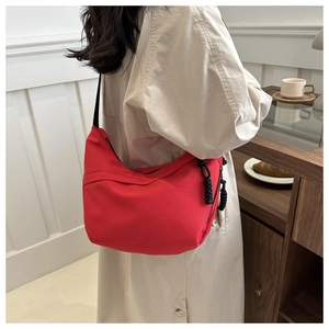 Detail of red crescent hobo bag with adjustable strap and dual zipper in lifestyle setting