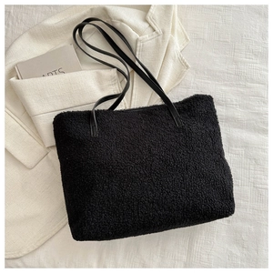 Détail d'un sac cabas noir en fausse fourrure montrant la texture douce et les anses