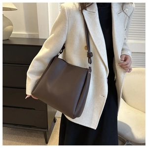 Detail of dark brown leather tote showing the knotted strap and smooth matte texture
