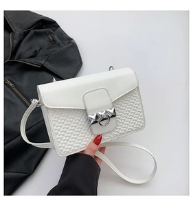 Detail of white PU leather crossbody bag featuring heart-shaped embossing and silver ring buckle