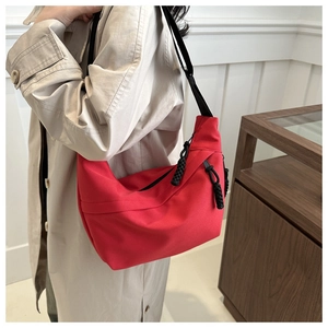 Side view of red crescent dumpling bag with black adjustable strap on shoulder