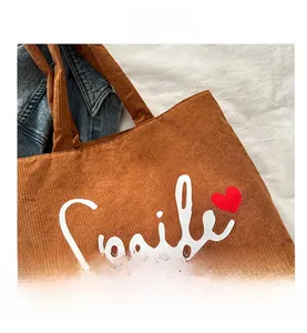 Detailed view of brown corduroy tote bag with Smile print and small red heart detail