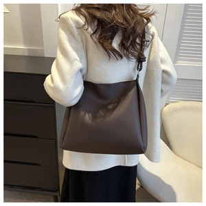 Detail of a vintage coffee brown tote bag showing a unique knotted shoulder strap and metal ring