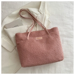 Détail du cabas en sherpa rose avec un patch logo en cuir sur un tissu doux texturé