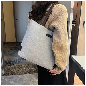 Detail of grey canvas tote bag with brown leather corners and FASHION brand patch