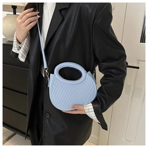 Detail der hellblauen halbrunden Handtasche mit vertikalen Plisseestreifen und Ringgriff