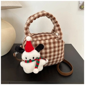 Dettaglio borsa a quadri con manico intrecciato e ciondolo a forma di peluche