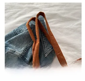 Close-up of brown corduroy tote bag handle stitching and soft ribbed fabric texture