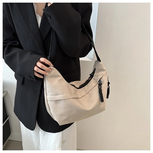 Detail of off-white dumpling shoulder bag with black woven zipper pull on model
