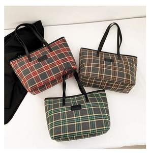 Detailed macro view of three plaid wool tote bags in red, brown, and green with leather straps