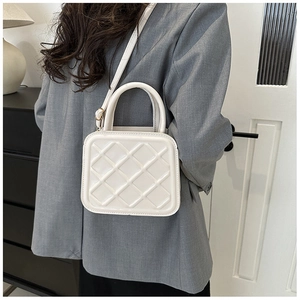 Detail of white quilted crossbody bag with chic diamond pattern and sturdy top handle