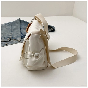 Vue détaillée du grand sac messager en toile crème avec cordon et charme biscuit