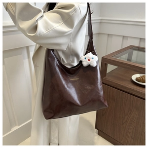 Close-up of a dark brown PU leather shoulder bag featuring a cute plush star charm detail