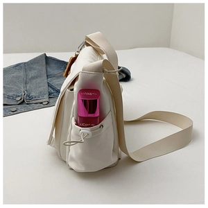 Détail du sac à bandoulière en nylon blanc montrant une poche latérale à cordon