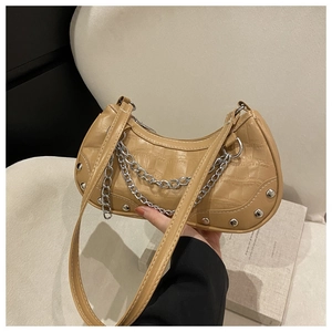 Détail du sac lune kaki montrant des clous argentés, des chaînes et une texture crocodile