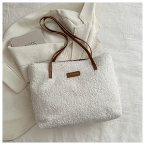 Gros plan d'un sac cabas en fausse fourrure blanche avec une étiquette en cuir marron