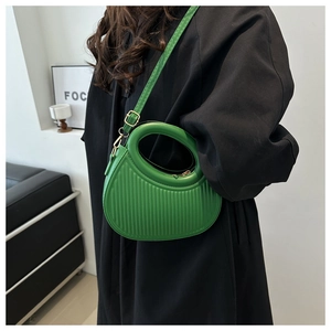 Detail der grünen gestreiften PU-Handtasche mit Rundgriff und goldenen Beschlägen