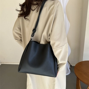 Minimalist black leather tote bag for women featuring a unique knotted shoulder strap